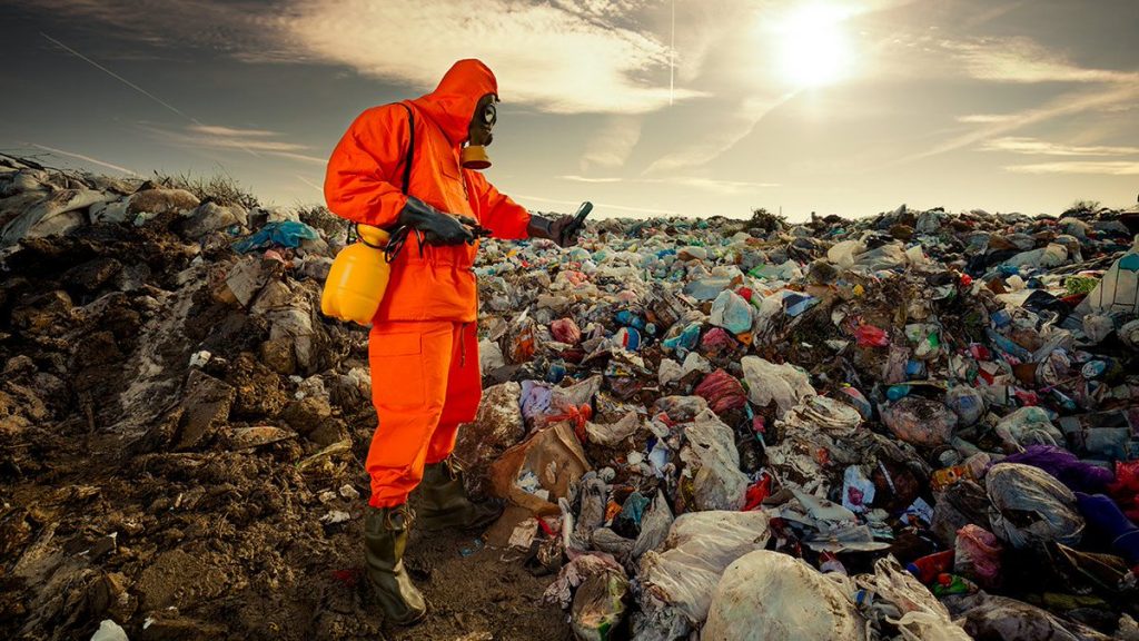 Hombre con traje de protección en montaña de basura 